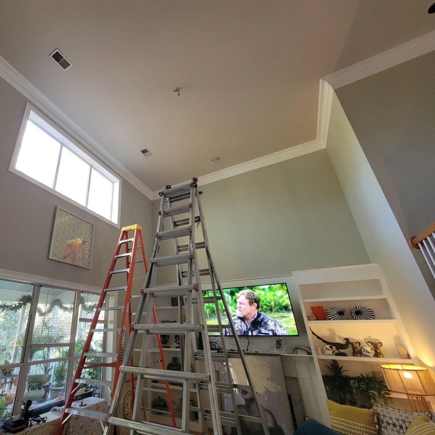 A ladder is sitting in a living room next to a television.