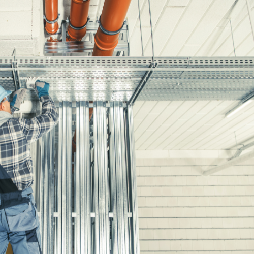 A man is working on a pipe system in a building.