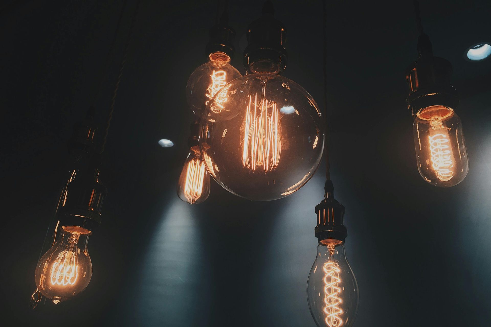 A bunch of light bulbs hanging from the ceiling in a dark room.