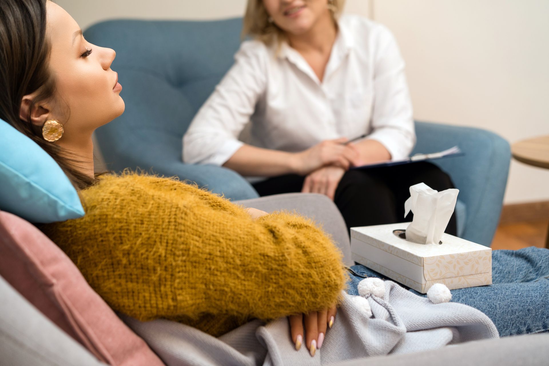 A woman is laying on a couch talking to a therapist.