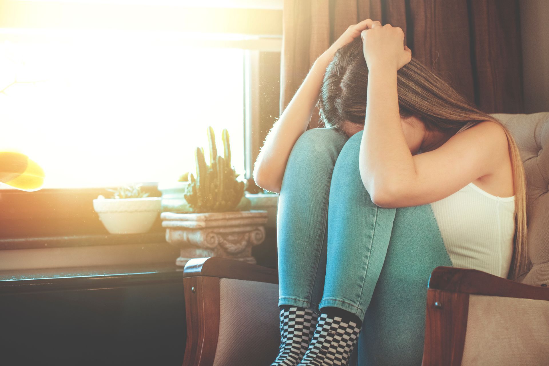 A woman is sitting in a chair with her head in her hands.