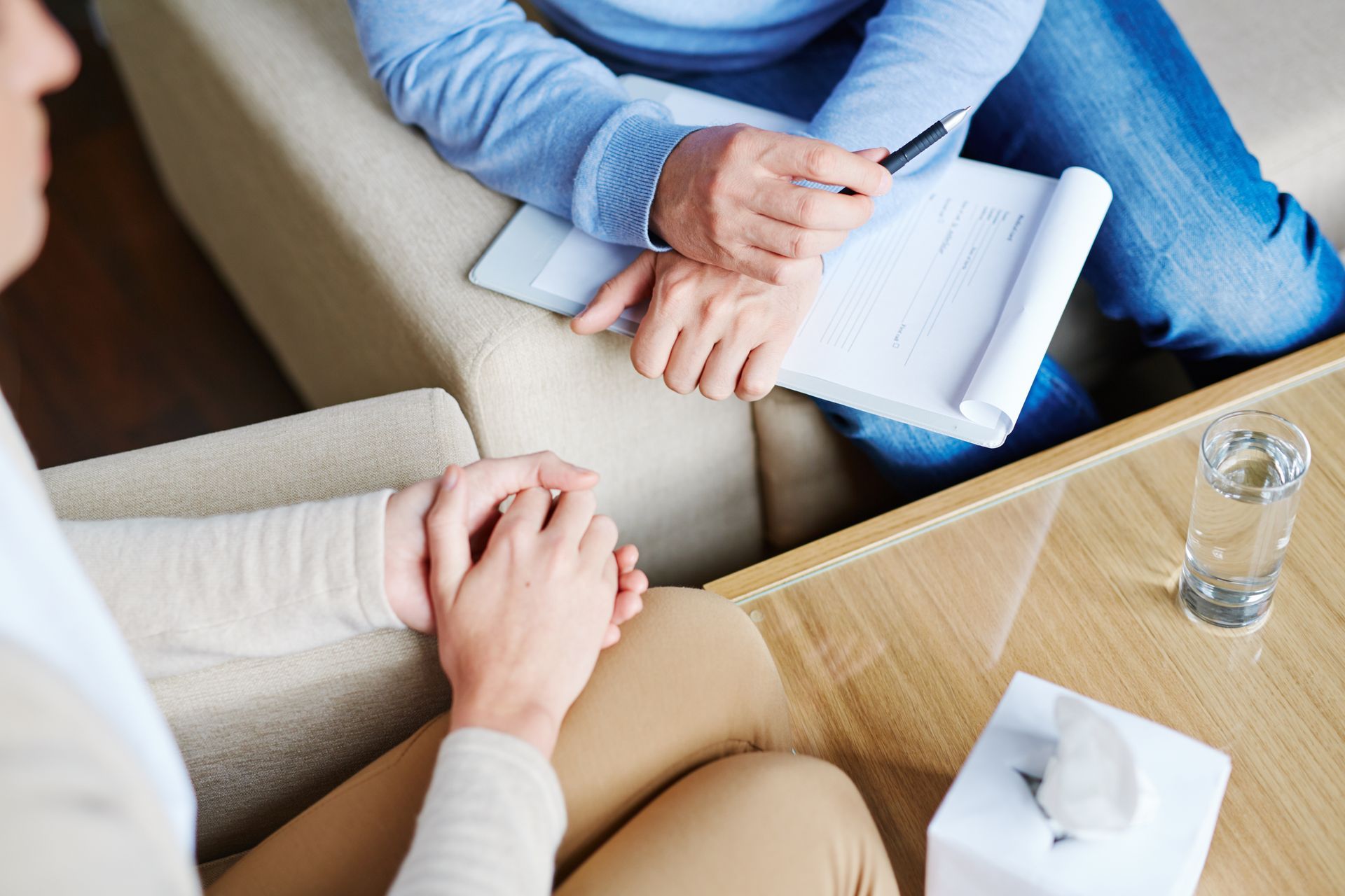 Close-up of a psychologist sitting next to his patient and listening to her story. Close-up of a psychologist sitting next to his patient and listening to her story.