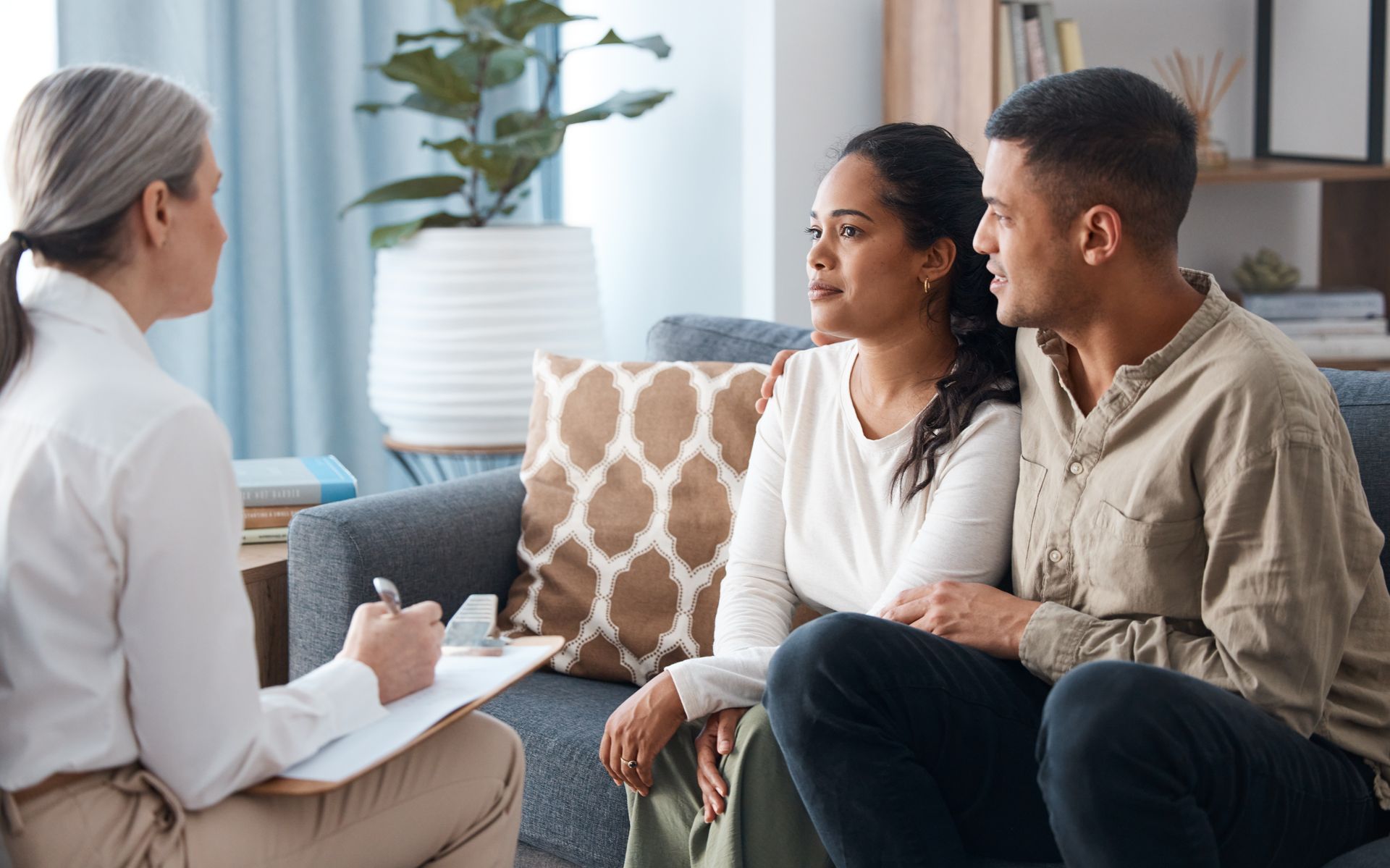 A couple on a sofa in front of a therapist for a marriage counselling session.