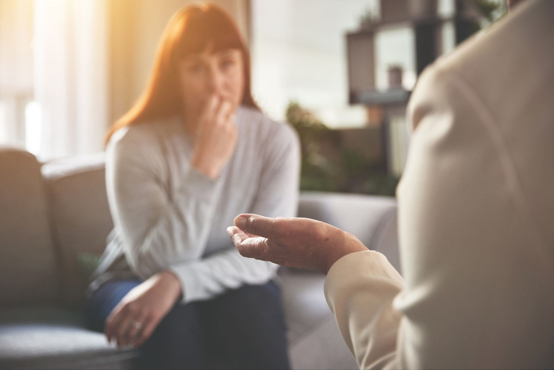 Two people sitting on a couch, one gesturing with hand. Two people sitting on a couch, one gesturing with hand.