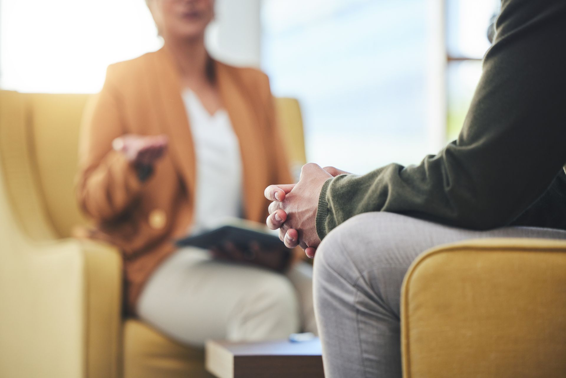 Two people sitting and talking, one holding a tablet.