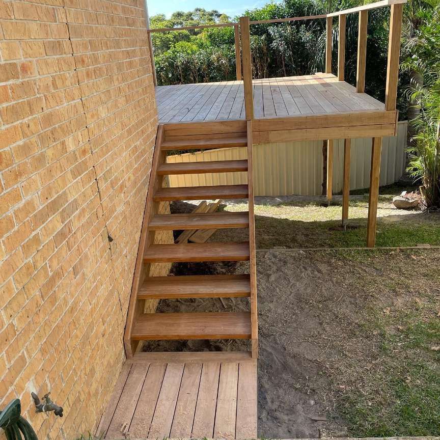 A Wooden Deck With Stairs Leading Up to It Next to a Brick Wall — Portstyle Constructions in Surfers Paradise, QLD