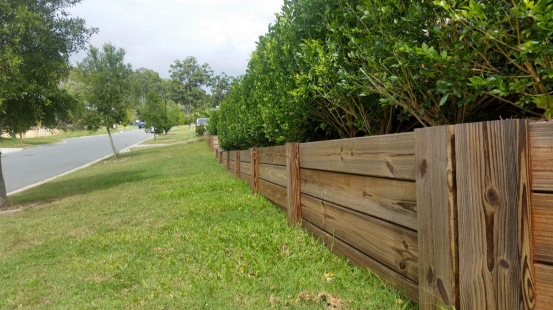 A timber retaining wall in the front yard of a residential property.