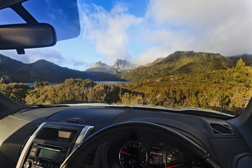 A Car Is Driving Down A Road With Mountains In The Background — Cam Duffy Autos In Atherton, QLD
