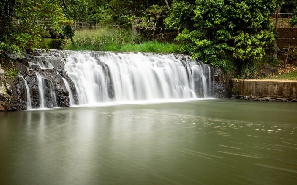 A Waterfall Is Surrounded By Trees And A Body Of Water — Cam Duffy Autos In Malanda, QLD