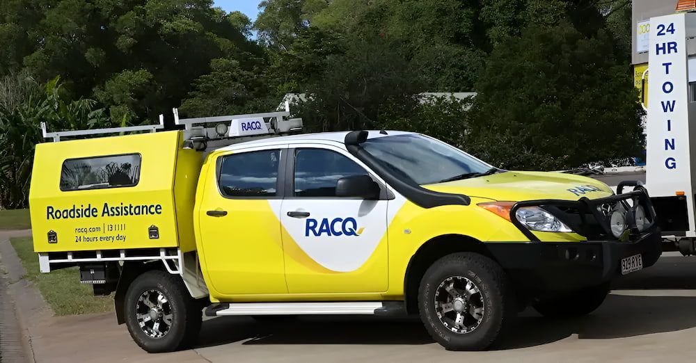 A Tow Truck With A Flat Bed Is On A Yellow Background — Cam Duffy Autos In Atherton, QLD