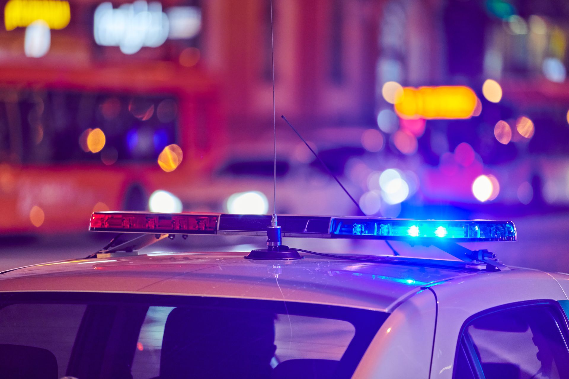 A police car with blue lights on top of it is parked on the street at night.