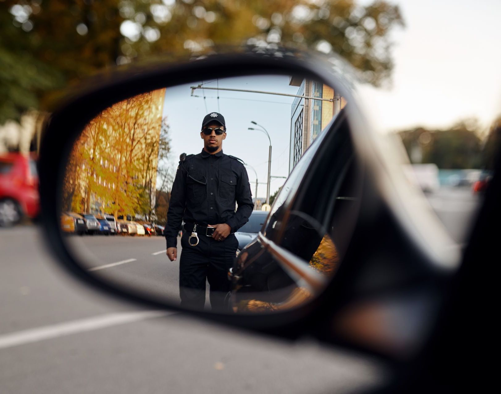 A police officer is reflected in the rear view mirror of a car