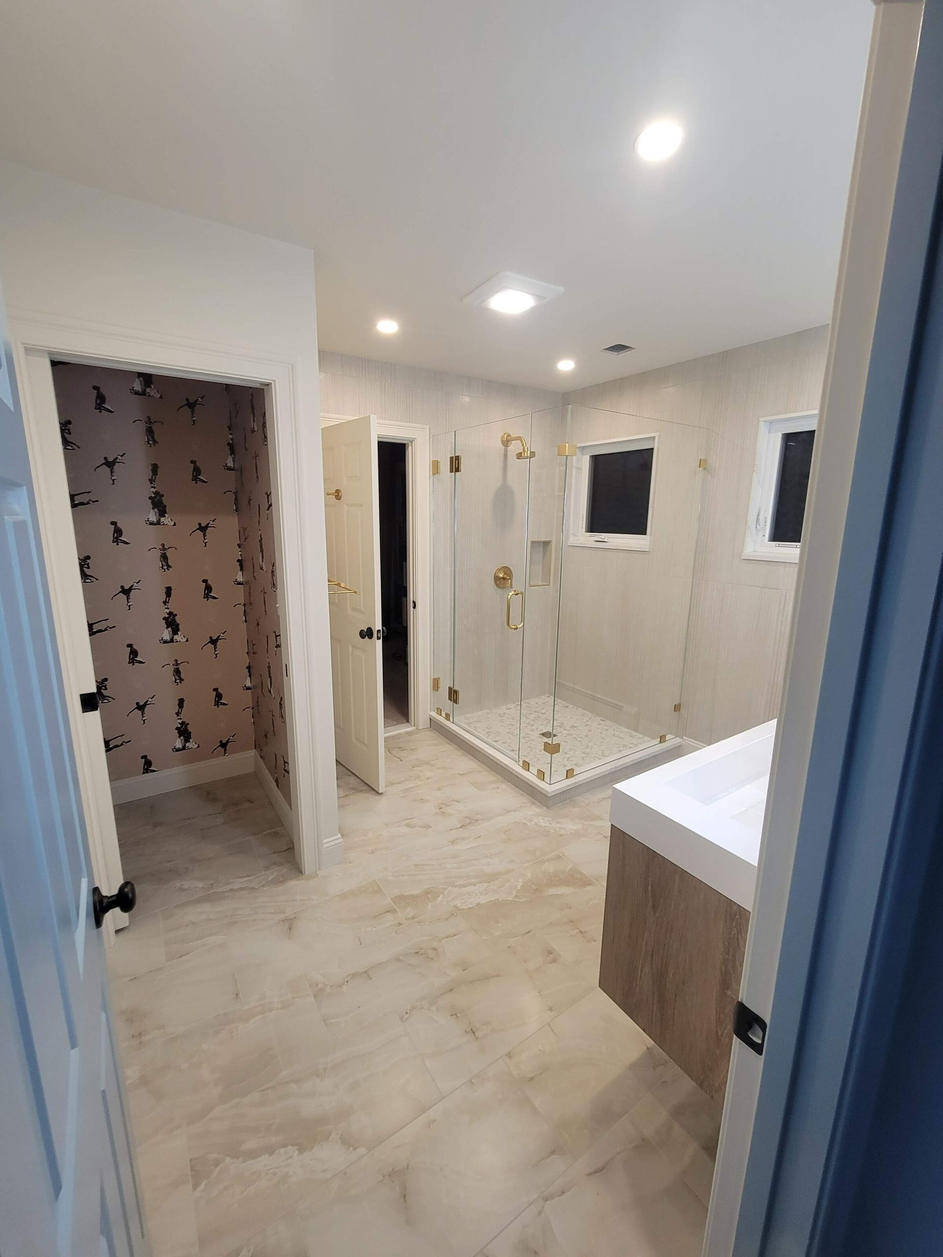 Bathroom with tile floor, glass shower, and vanity. Doorways lead to other rooms.