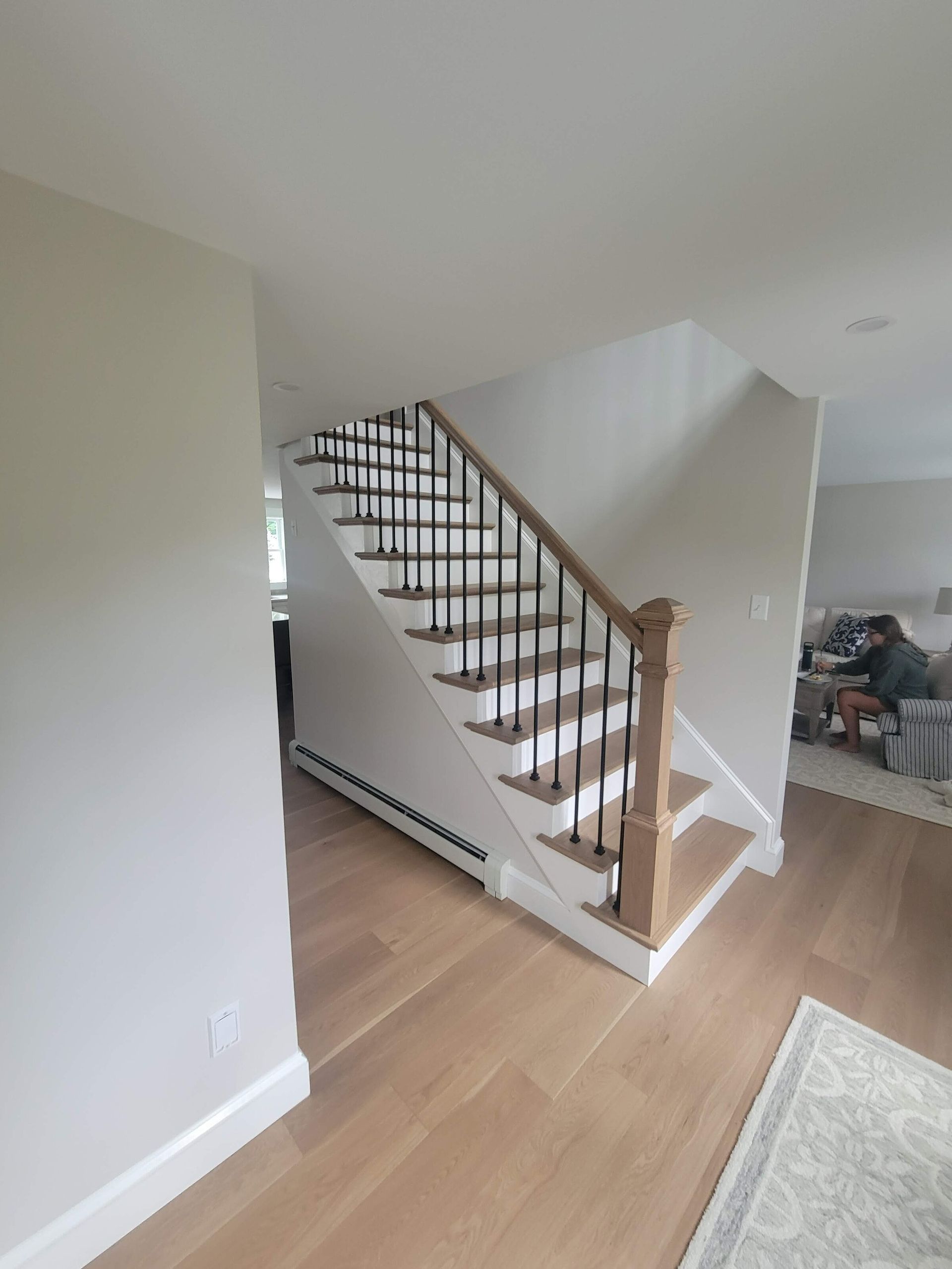 Staircase with wooden steps and railing, black spindles, leading to upper level in a home.