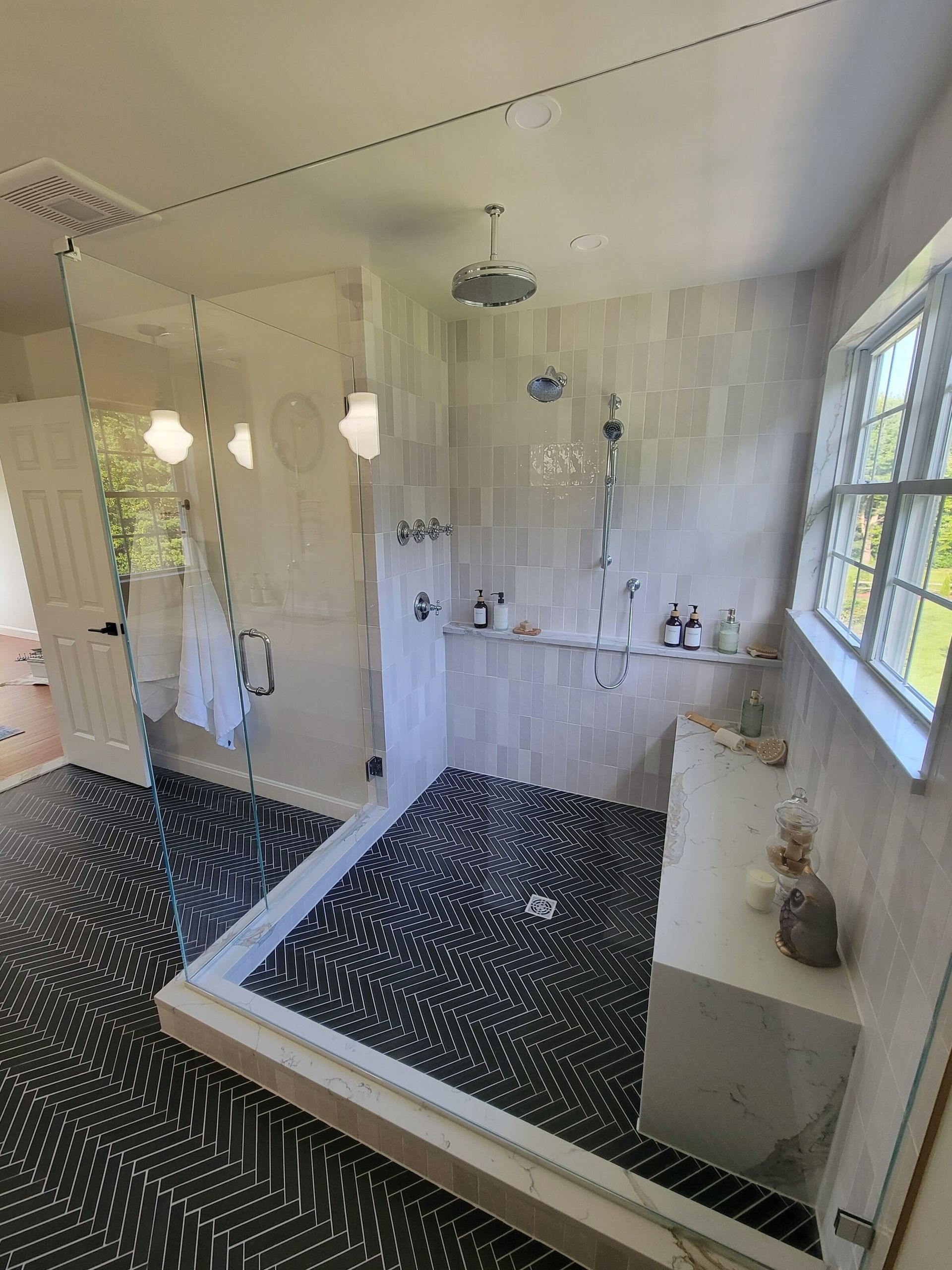 Modern bathroom with glass shower, patterned floor, and white walls.