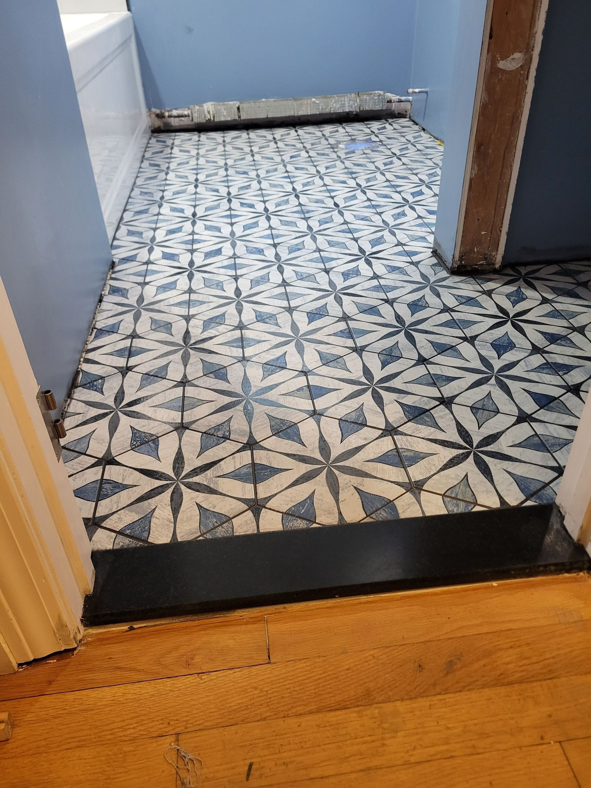 Blue and white patterned tile flooring in a bathroom, viewed from the doorway.