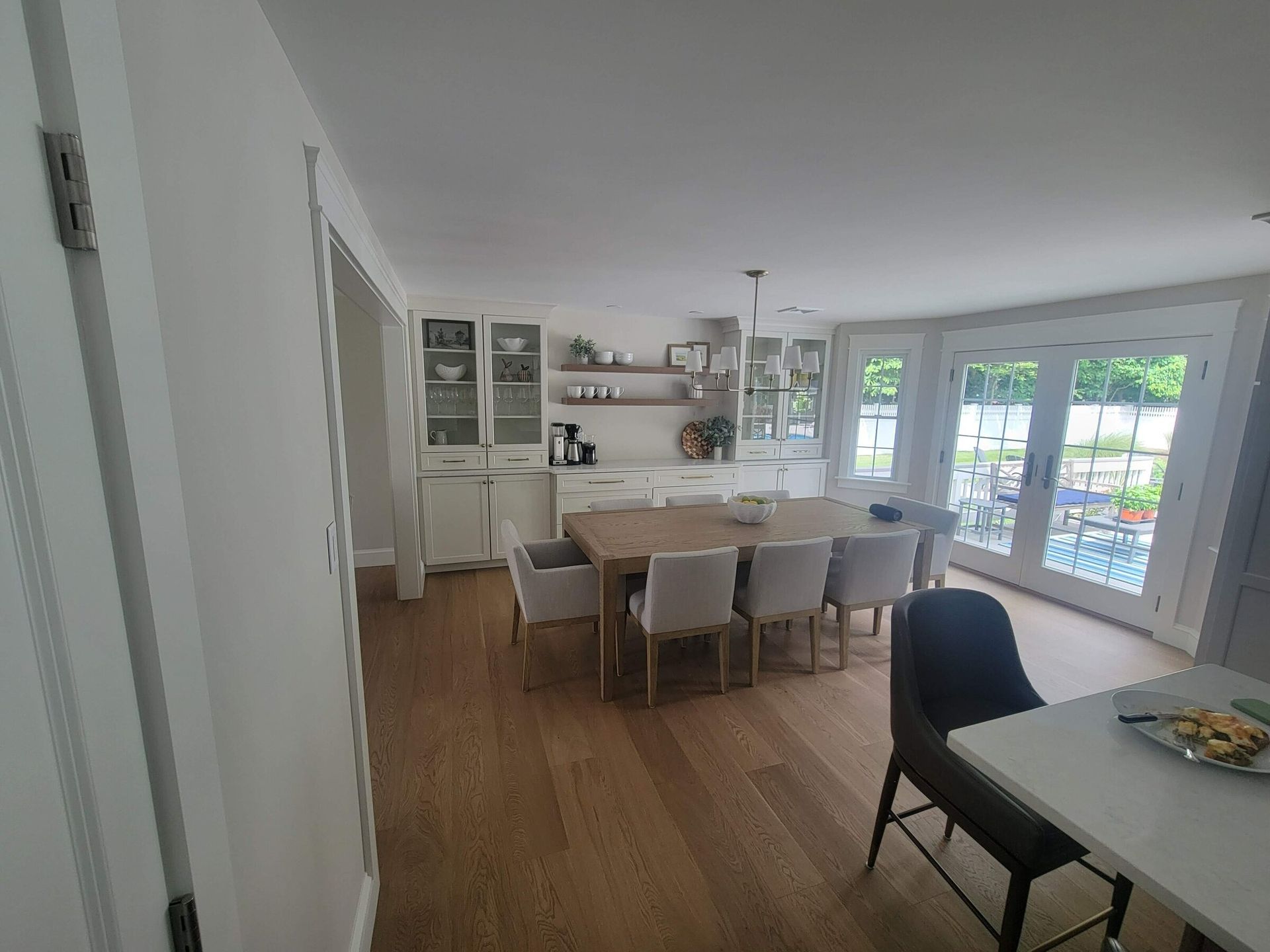 Dining room with a wooden table and chairs, hardwood floor, cabinets, and French doors to the outside.