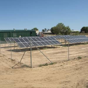A row of solar panels sitting on top of a dirt field.