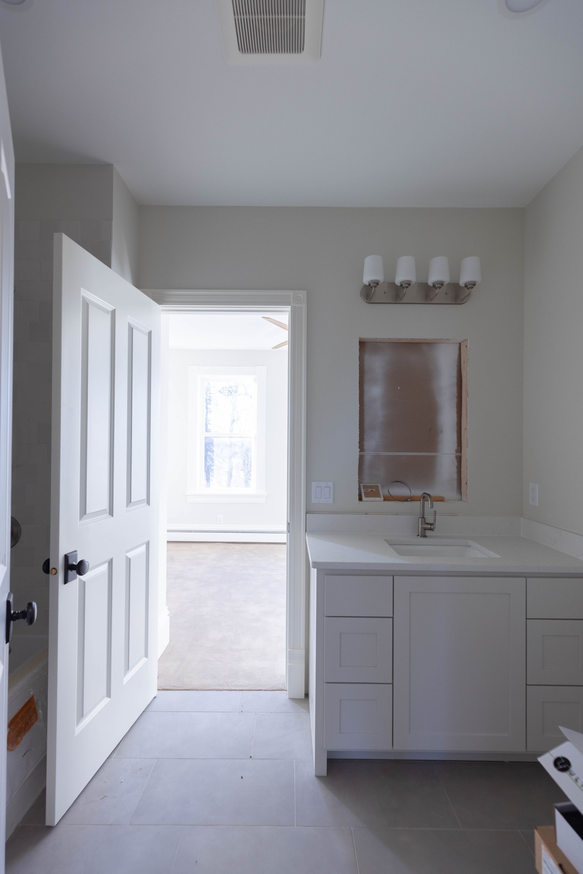 A bathroom with white cabinets , a sink and a mirror.