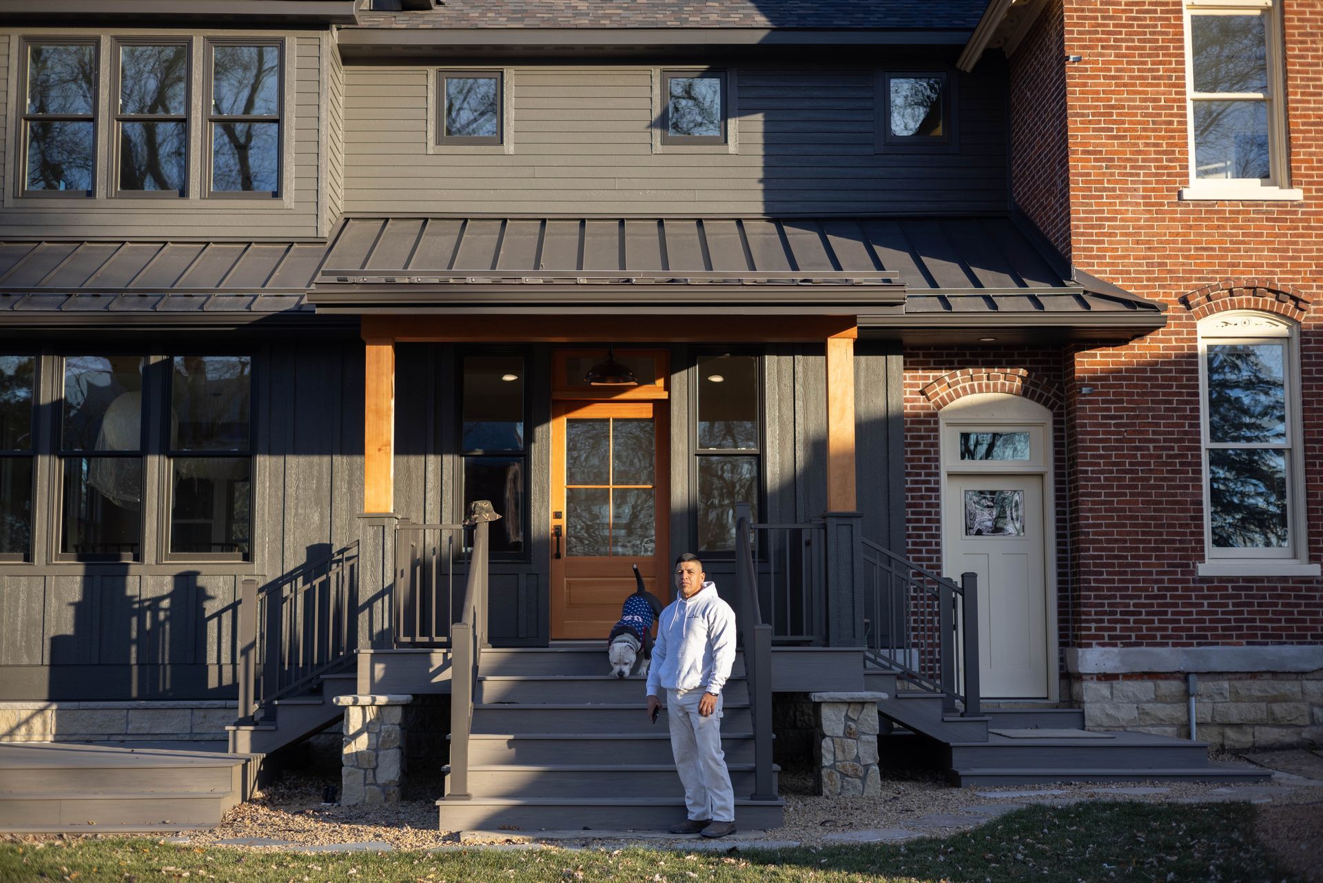 A man is standing in front of a large brick house