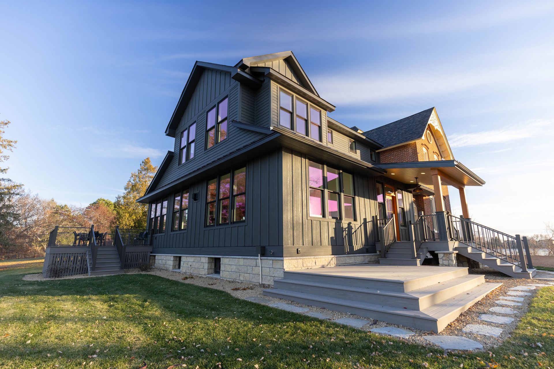 A large house with a lot of windows is sitting on top of a lush green field.