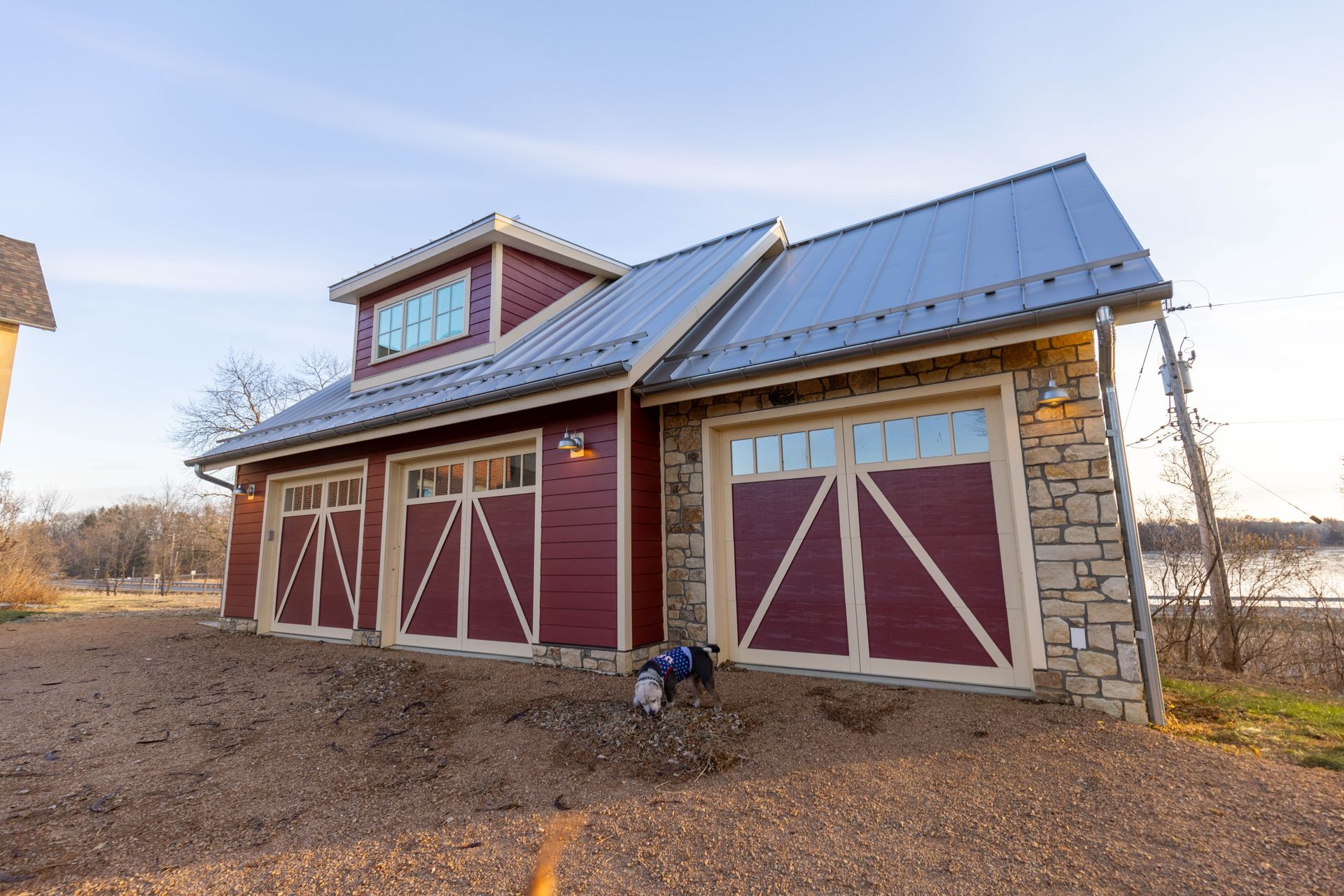 A dog is standing in front of a red garage with a blue roof.