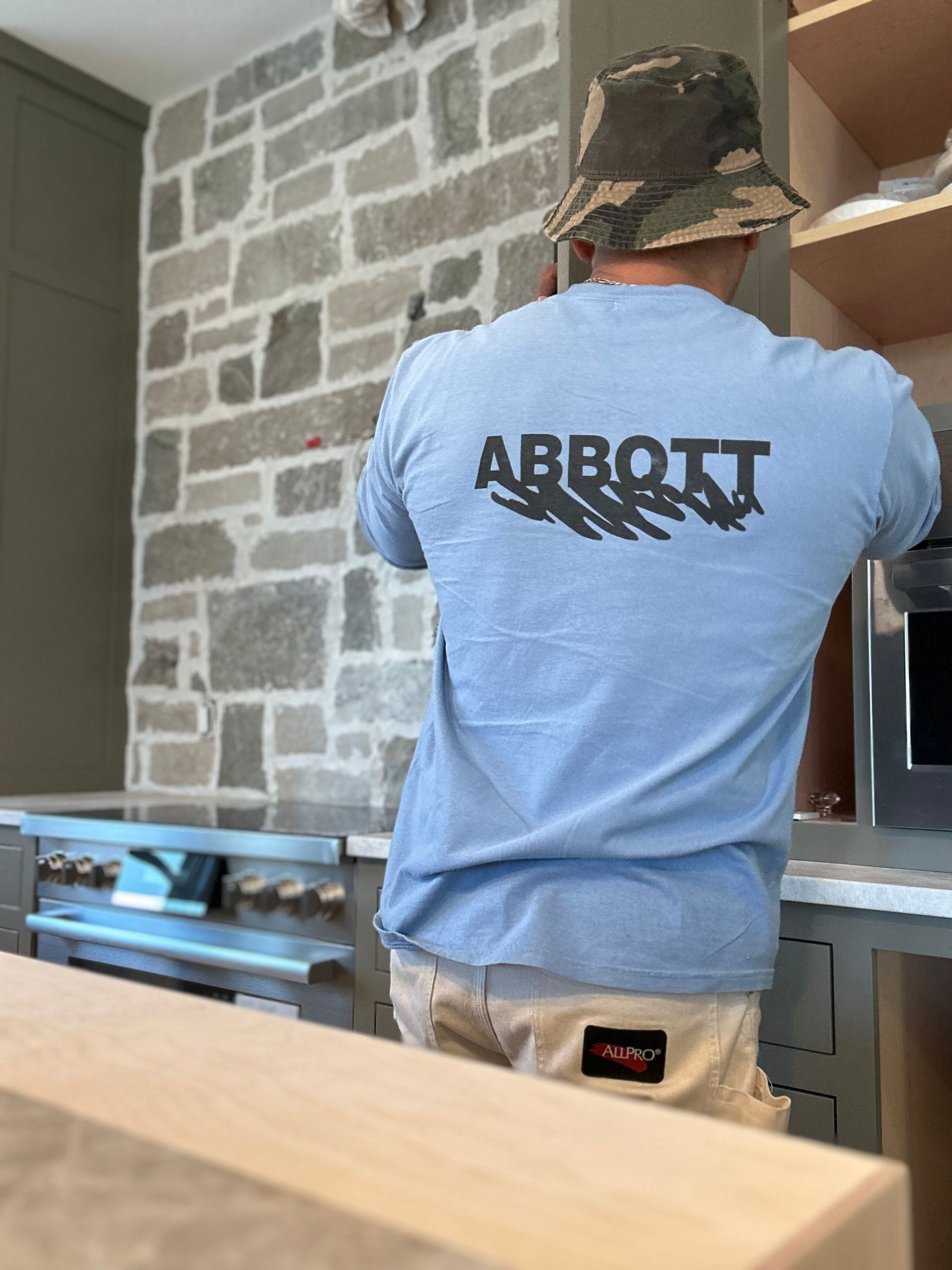 A man wearing a light blue t-shirt with the word abbott on it