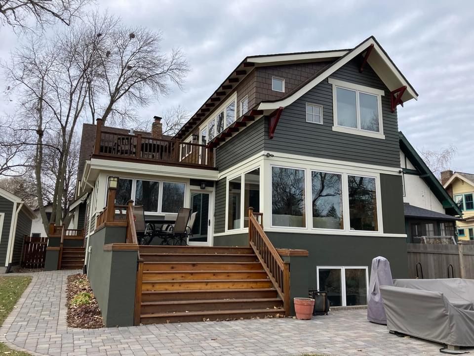 The back of a large house with a large deck and stairs.