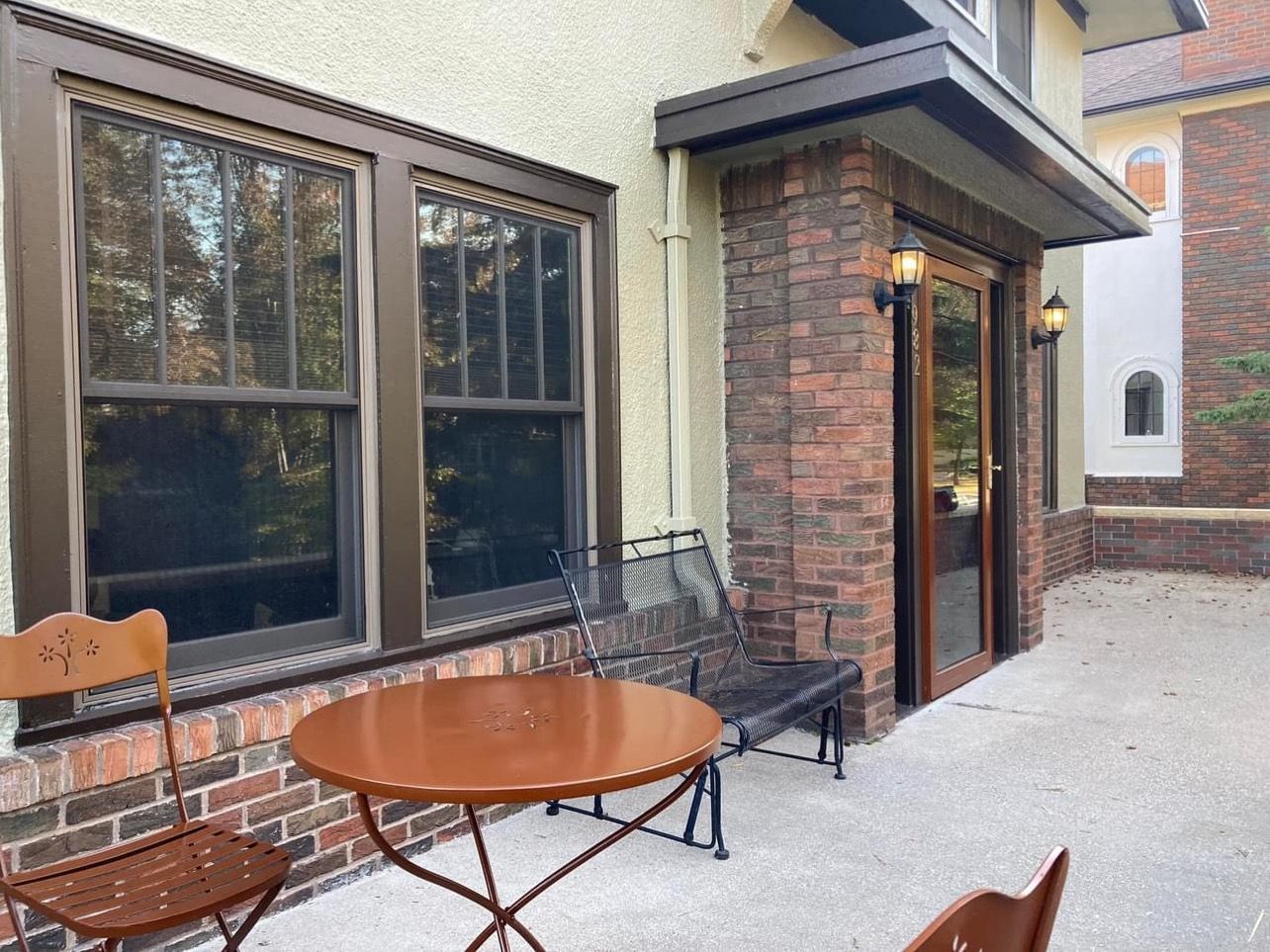 A patio with a table and chairs in front of a brick building.