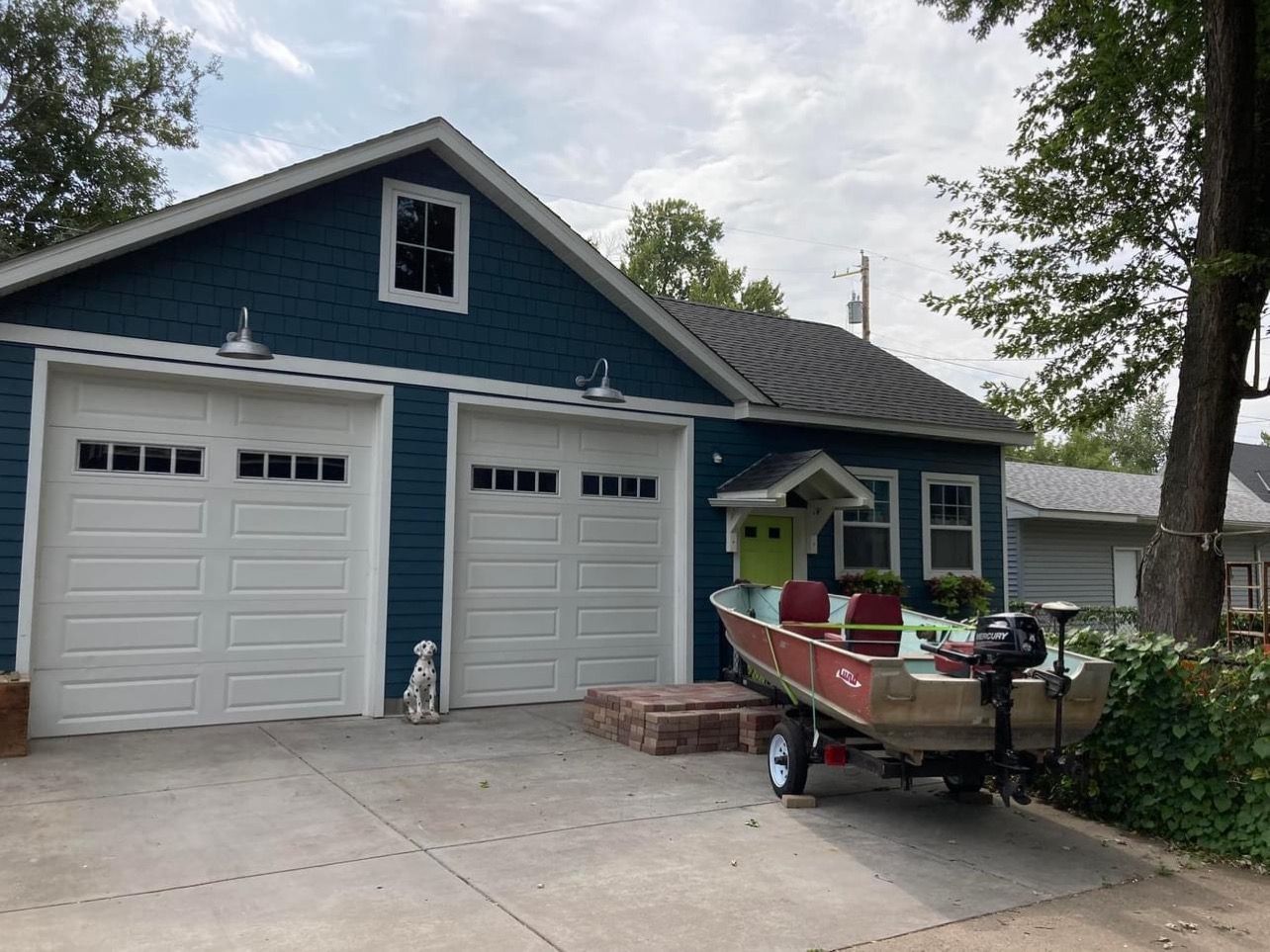 A boat is parked in front of a blue house.
