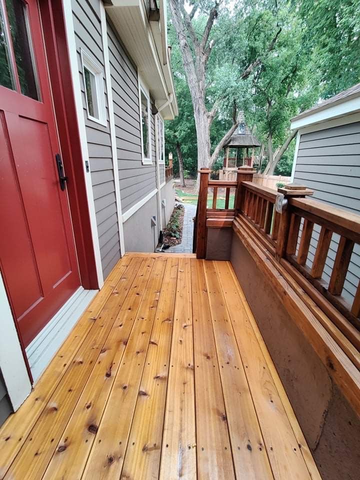 A wooden deck with a bench in front of a house.