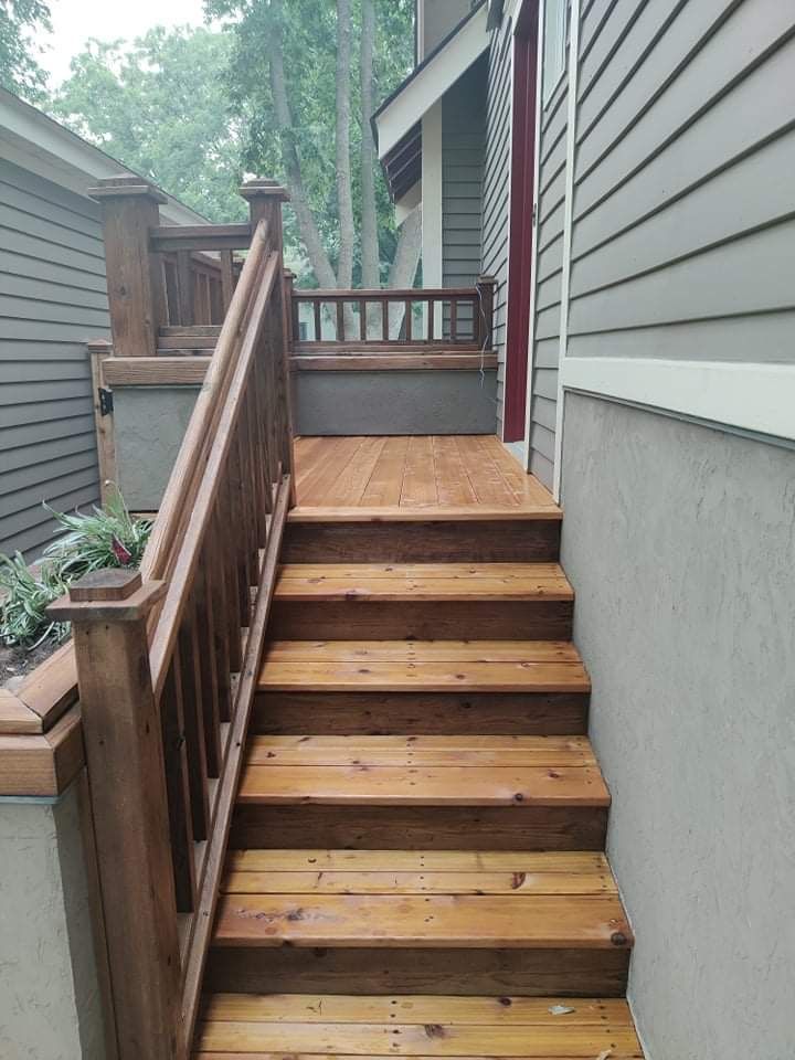 A wooden deck with stairs leading up to it next to a house.