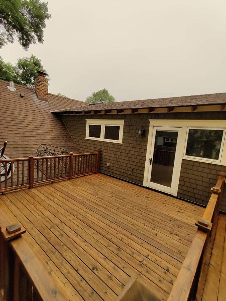There is a large wooden deck in front of a house.