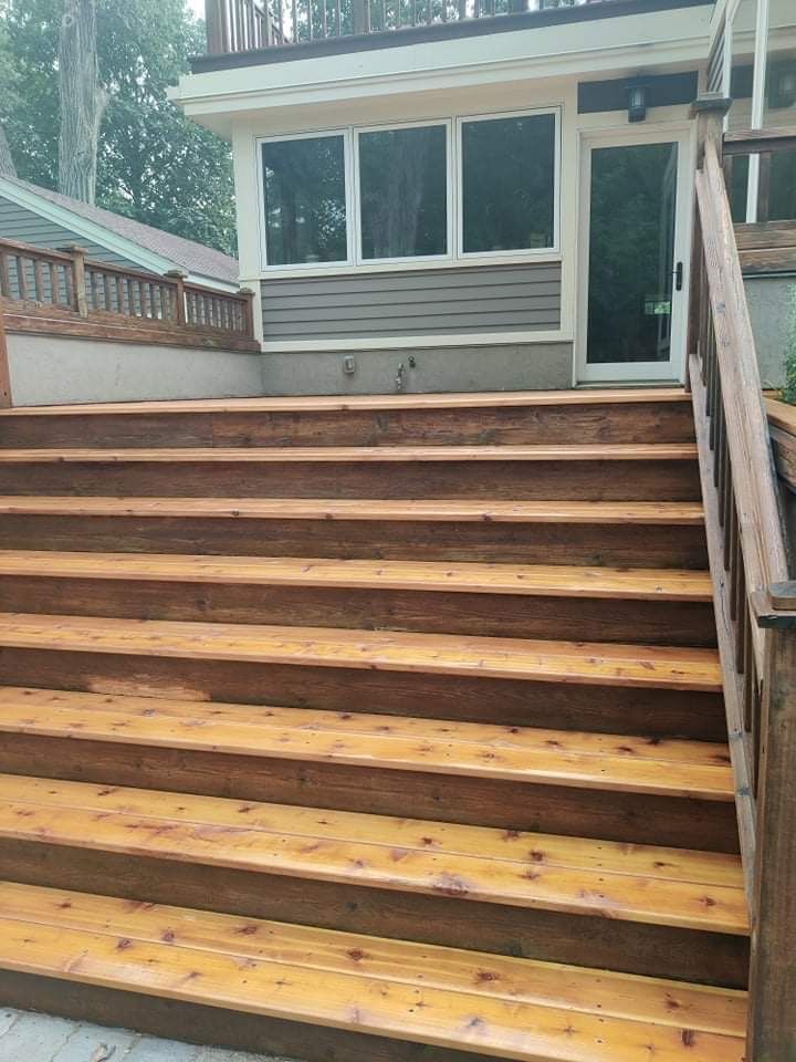 A wooden deck with stairs leading up to a house.