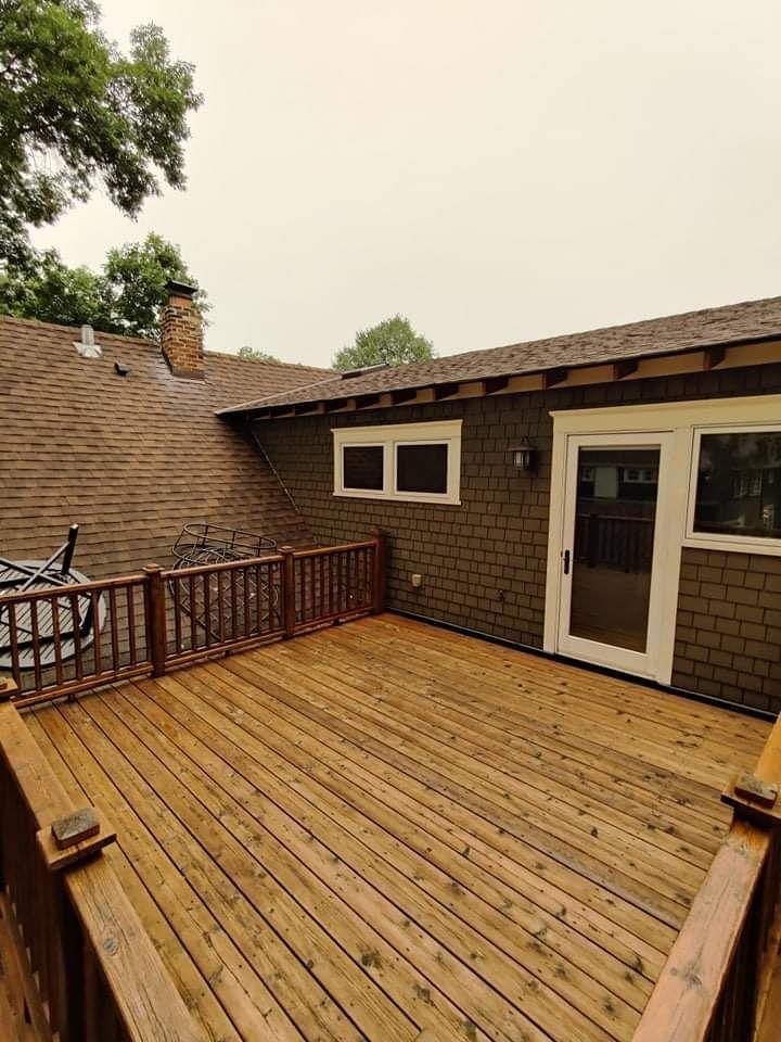 There is a large wooden deck in front of a house.