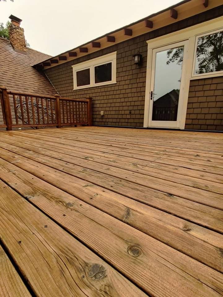 A wooden deck in front of a brick house with a sliding glass door.
