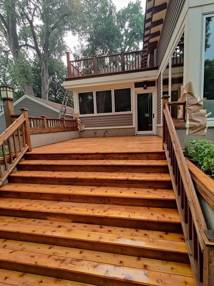 A wooden deck with stairs leading up to it and a house in the background.