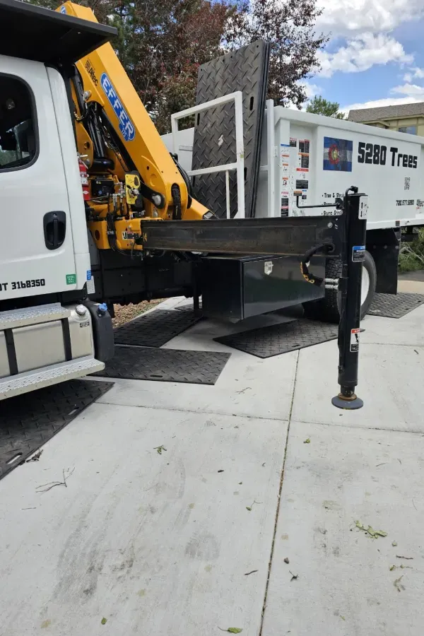 A yellow crane is attached to the back of a dump truck.