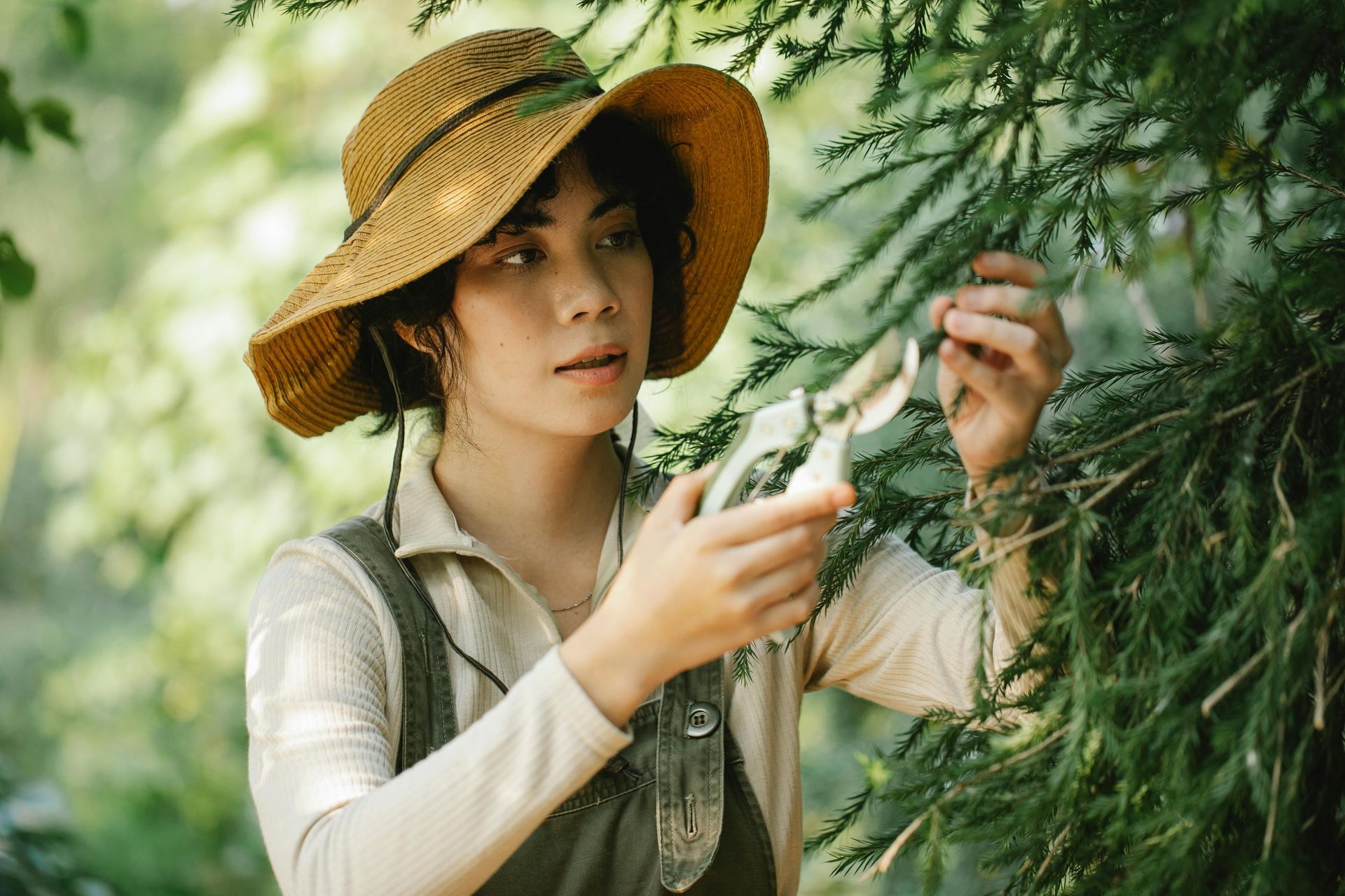 A woman in a straw hat is standing next to a tree.