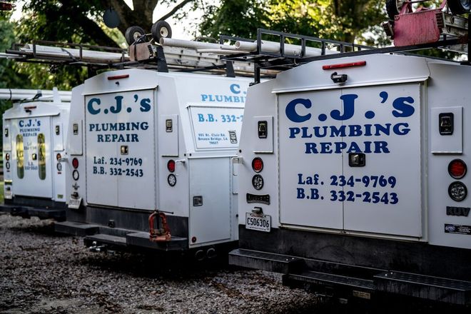 C.J.’s Plumbing Repair trucks parked side by side, with white panels and blue lettering.