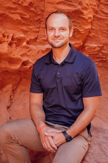 A man in a blue shirt is sitting on a rock.