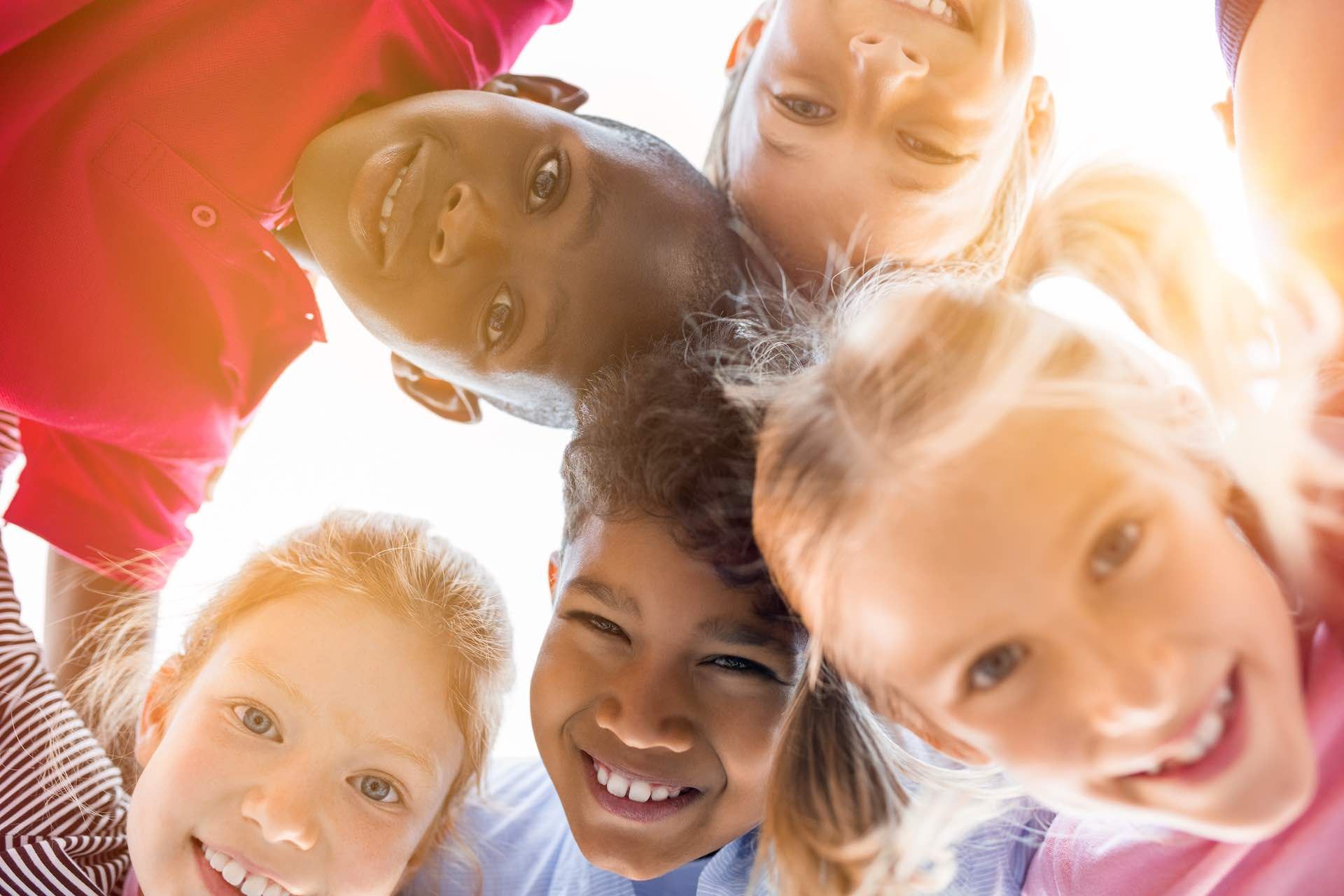 A group of children are standing in a circle and smiling at the camera.