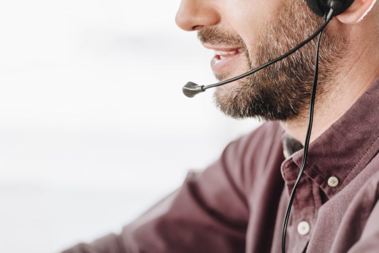 A man with a beard is wearing a headset while talking on a phone.