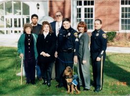 A group of people posing for a picture with a police dog