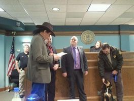 A group of men are standing in a room with a dog.