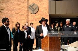 A man in a cowboy hat is standing at a podium in front of a group of people.