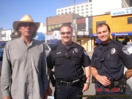 A man in a cowboy hat is posing for a picture with two police officers
