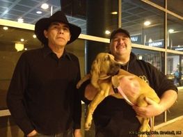 Two men standing next to each other holding a dog