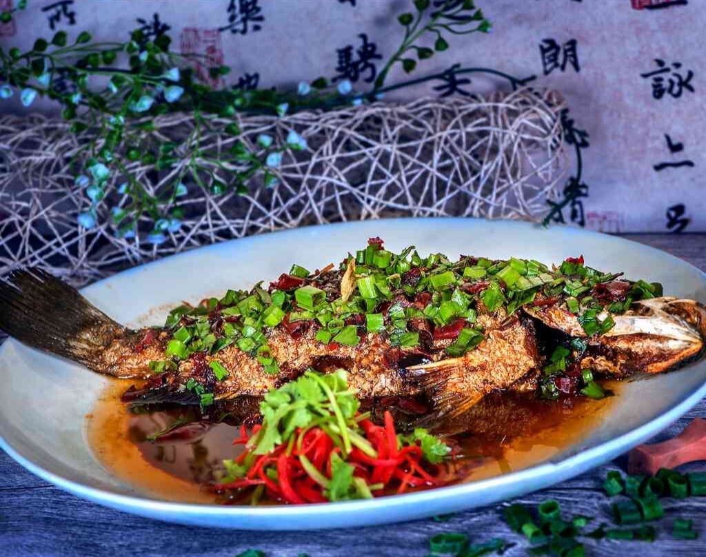A white plate topped with a fish and vegetables on a table.