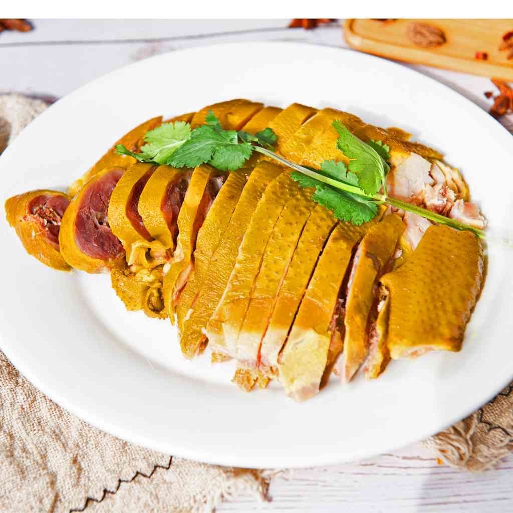 A white plate topped with sliced chicken and parsley on a table.